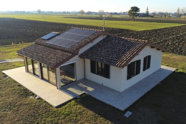 La casa in legno presenta un caratteristico tetto a più pendenze ed è dotata di pannelli solari.